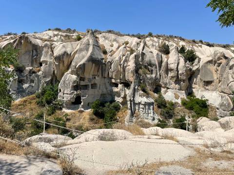 Cave dwellings in rocky landscape with greenery.