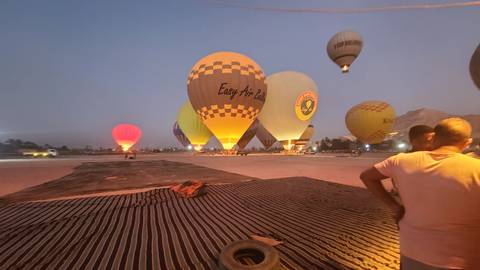 Hot air balloons being prepared for flight at dusk.