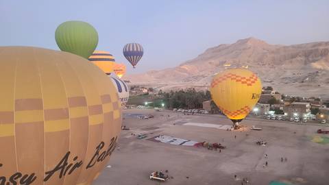 Hot air balloons over a vast desert landscape.