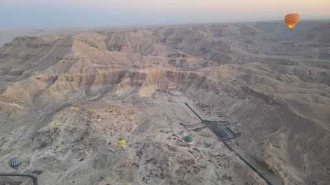 Hot air balloons floating over desert canyon.