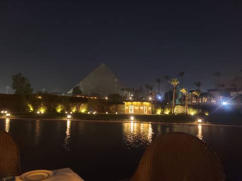 Pyramid illuminated at night with reflection in water.