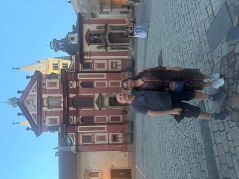 Couple posing in front of a historic red building.