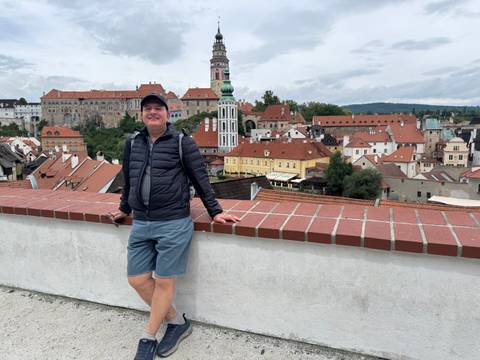 Man leaning on a wall with a panoramic view of a historic town.