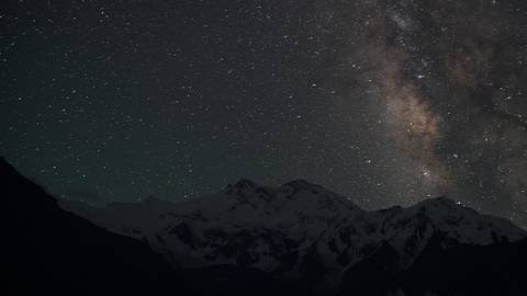 Milky Way over snow-capped mountains at night.