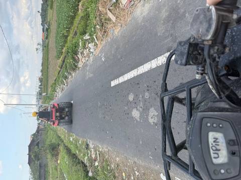 ATVs on a rural road with cloudy skies overhead.