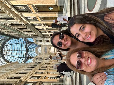 Three people posing inside a grand Galleria with a glass dome ceiling.