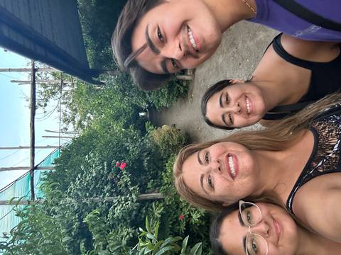 Four people posing in a gardened pathway setting.