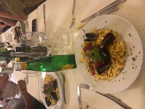 Seafood pasta dish served with water and a table setting.