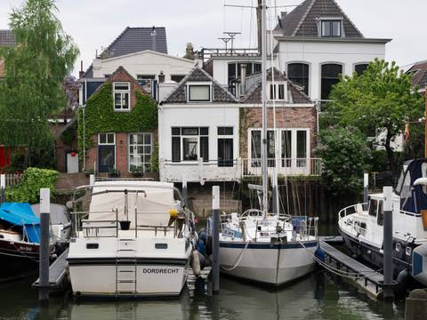 Docked boats with charming, ivy-covered houses along a canal.