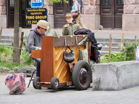 Street musician playing a piano outdoors with a child watching.