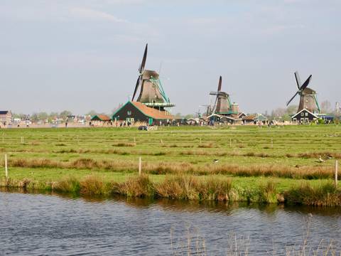 Windmills in a pastoral landscape with open fields and canals.