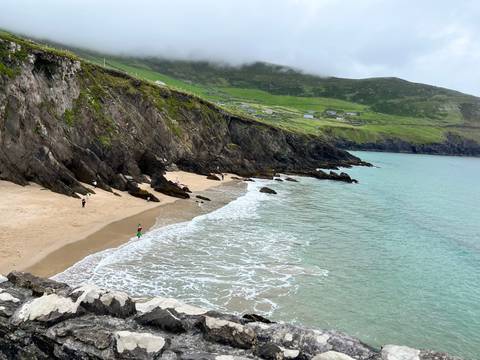 People walking along a rocky beach coastline.