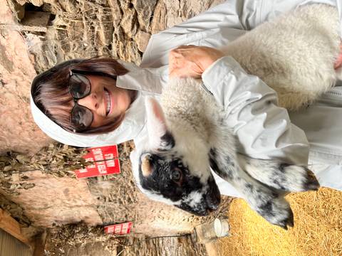 Woman holding a lamb in a barn.