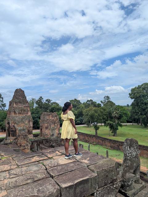 Woman standing on ancient ruins overlooking lush landscape.
