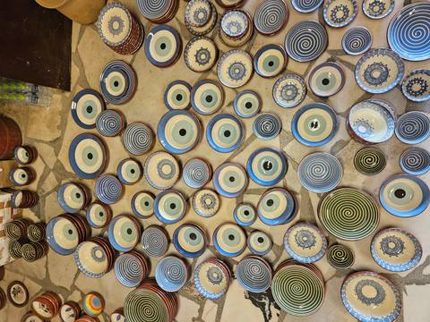 Colourful handcrafted dishes laid out on a stone floor.
