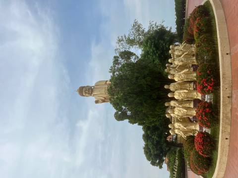 Golden statue surrounded by smaller statues and flowers.