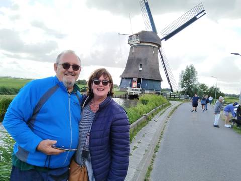 A couple posing in front of a windmill in a scenic location.