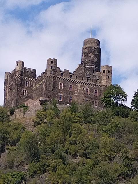 A castle on a hill with turrets and a stone wall.