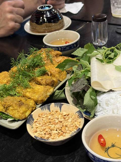 Vietnamese dish with herbs, noodles, and grilled items.