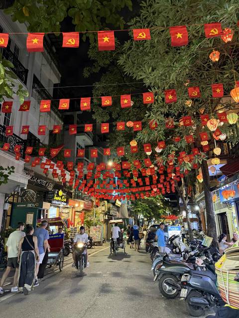 Hanoi street decorated with Vietnamese flags and lanterns at night.
