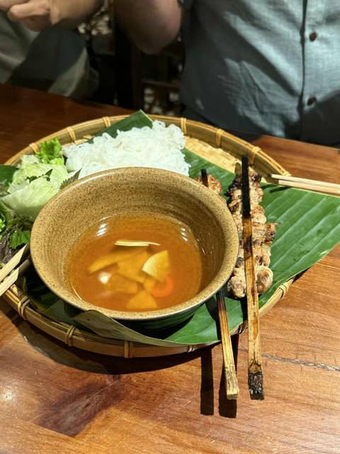 Vietnamese dining setting with grilled food and dipping sauce.