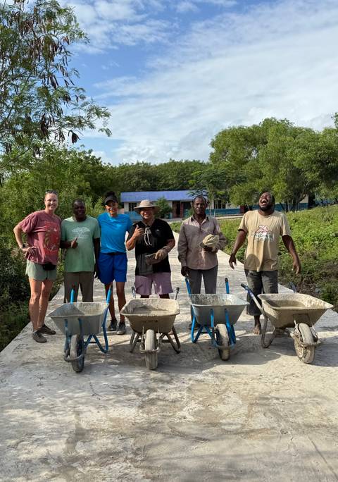 Group of people with wheelbarrows on a path.