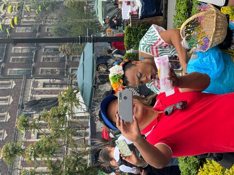 People wearing traditional clothing and capturing photos in a market setting.