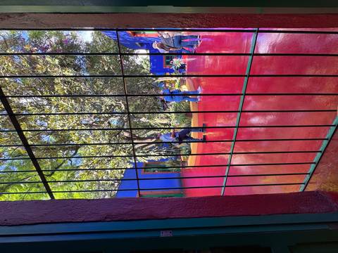 Outdoor space with people sitting on brightly colored flooring with a blue wall.