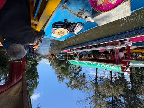 People on colorful boats navigating a water canal.