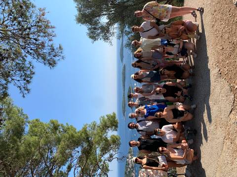 Group of tourists posing at a viewpoint overlooking the sea.