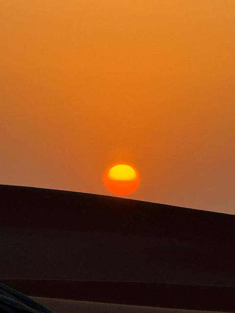 Bright orange sun setting over a sand dune.