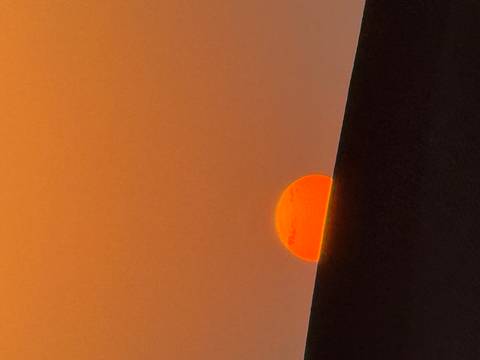 Red sun setting over distant hills.