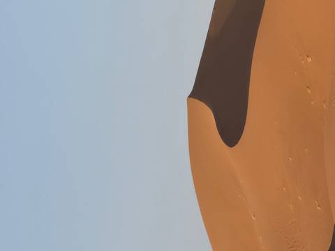 Smooth sand dunes under blue sky.