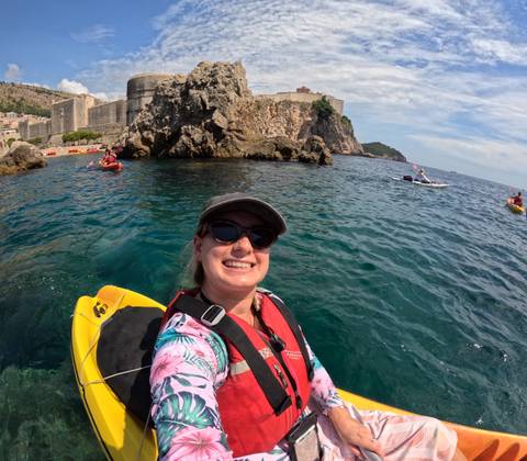 Selfie of a person kayaking near a rocky shore.