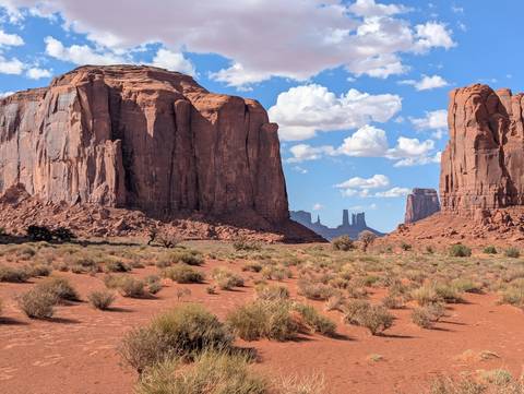 Vast desert landscape with rock formations under a blue sky.