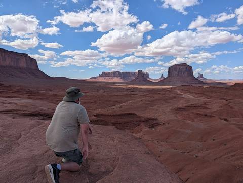 Person sitting on a rock overlooking a desert landscape.