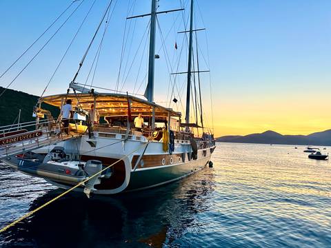 Sailboat anchored at sunset with glowing lights.
