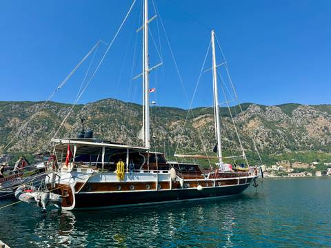 Anchored sailboat with mountainous backdrop.
