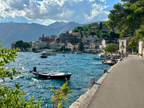 Coastal town with boats and lush hills in the background.