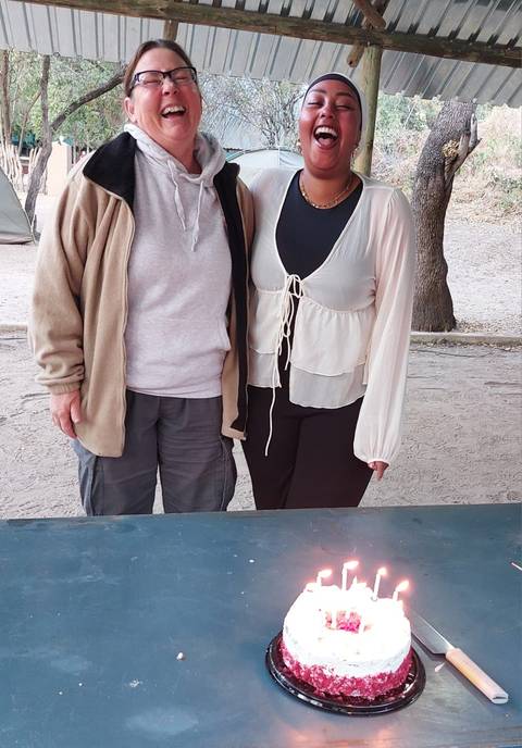 Partial view of two people standing next to a picnic table.
