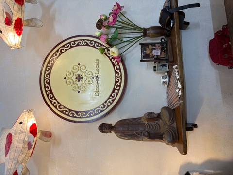 Decorative wall with a 'Dine with Locals' plaque and a Buddha statue.