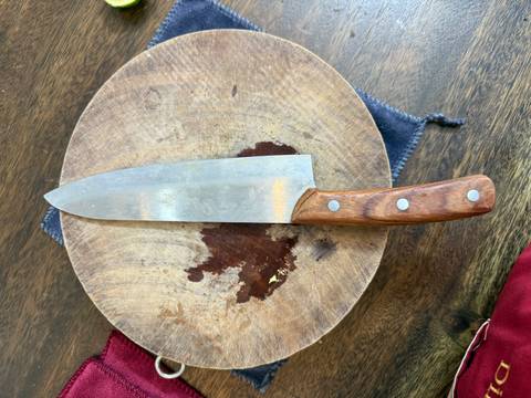 A close-up of a knife on a wooden cutting board.