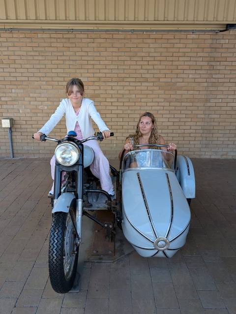 Two people enjoying a vintage motorcycle with a sidecar.