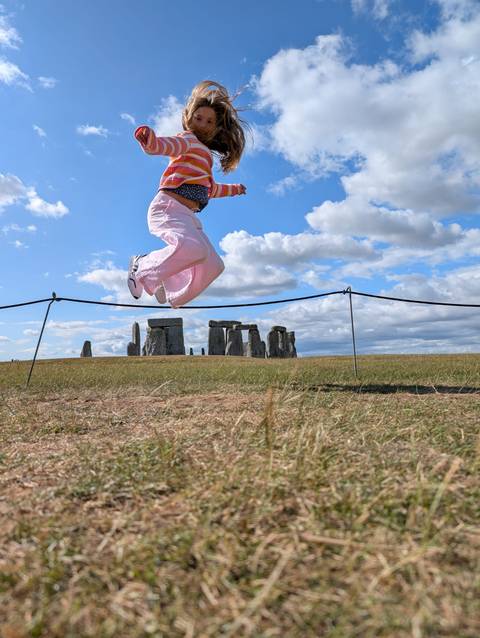 A person jumping near the historic monument of Stonehenge.