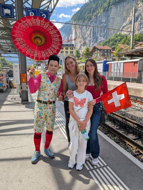 A group of people posing at a train station holding a Swiss flag.