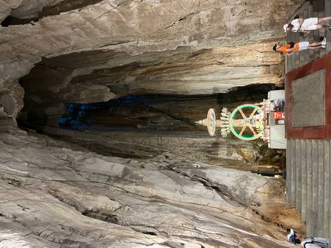 People exploring a large cave interior with a colorful altar.