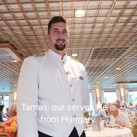 A person in a uniform posing inside a dining area.