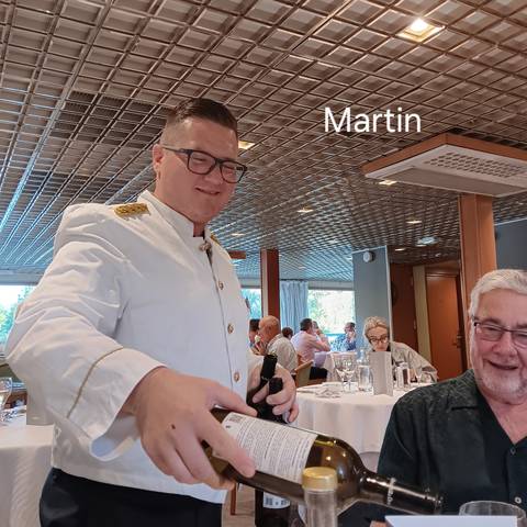 Person serving wine in a dining area.