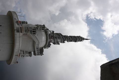 Tall stupa structure against a cloudy sky.