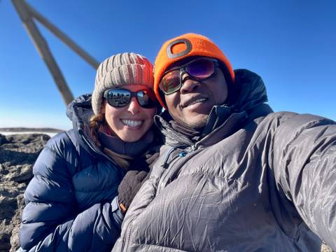 Couple in warm clothing taking a selfie on a mountain peak.